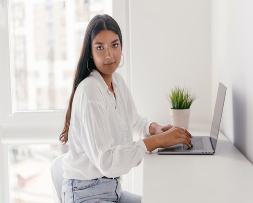 A person gently rolling their shoulders back while taking a short break from typing on a laptop