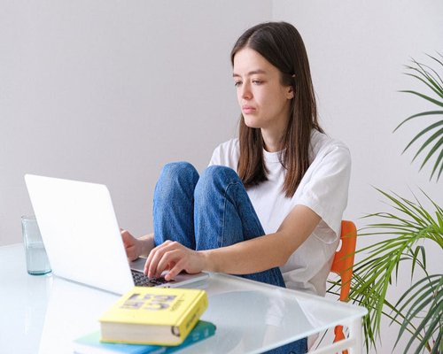 A person working from home with a laptop elevated on books for better neck posture